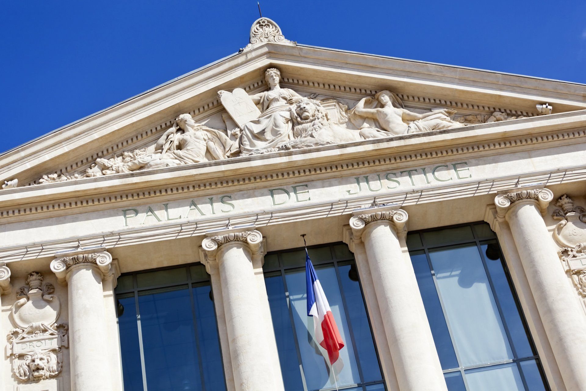 Façade d'un palais de justice, fronton sculpté et drapeau français